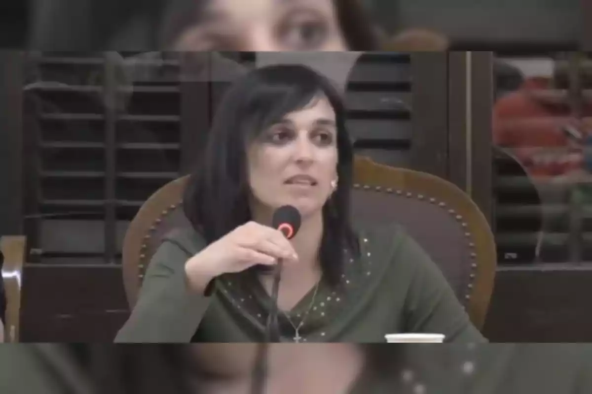 Una persona hablando en un micrófono durante un evento o conferencia.