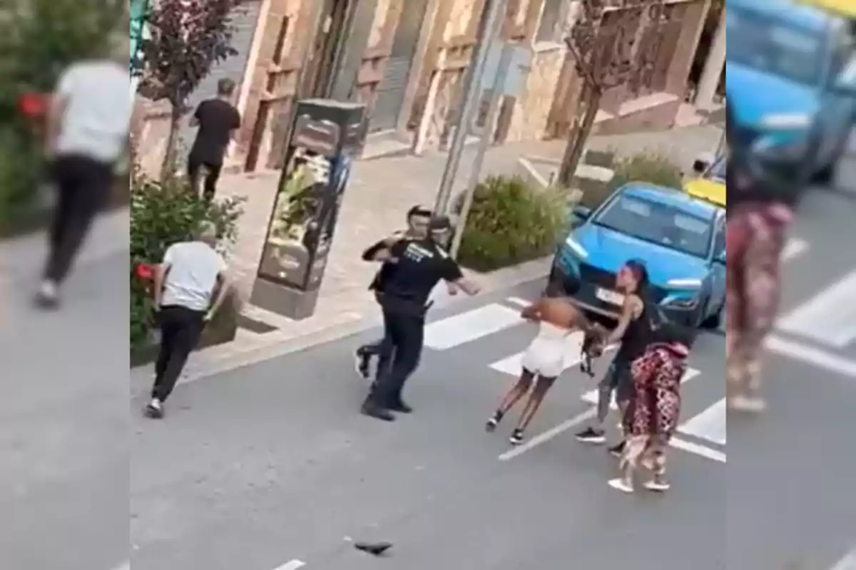 Una escena en la calle donde varias personas están interactuando, con un coche azul estacionado cerca.