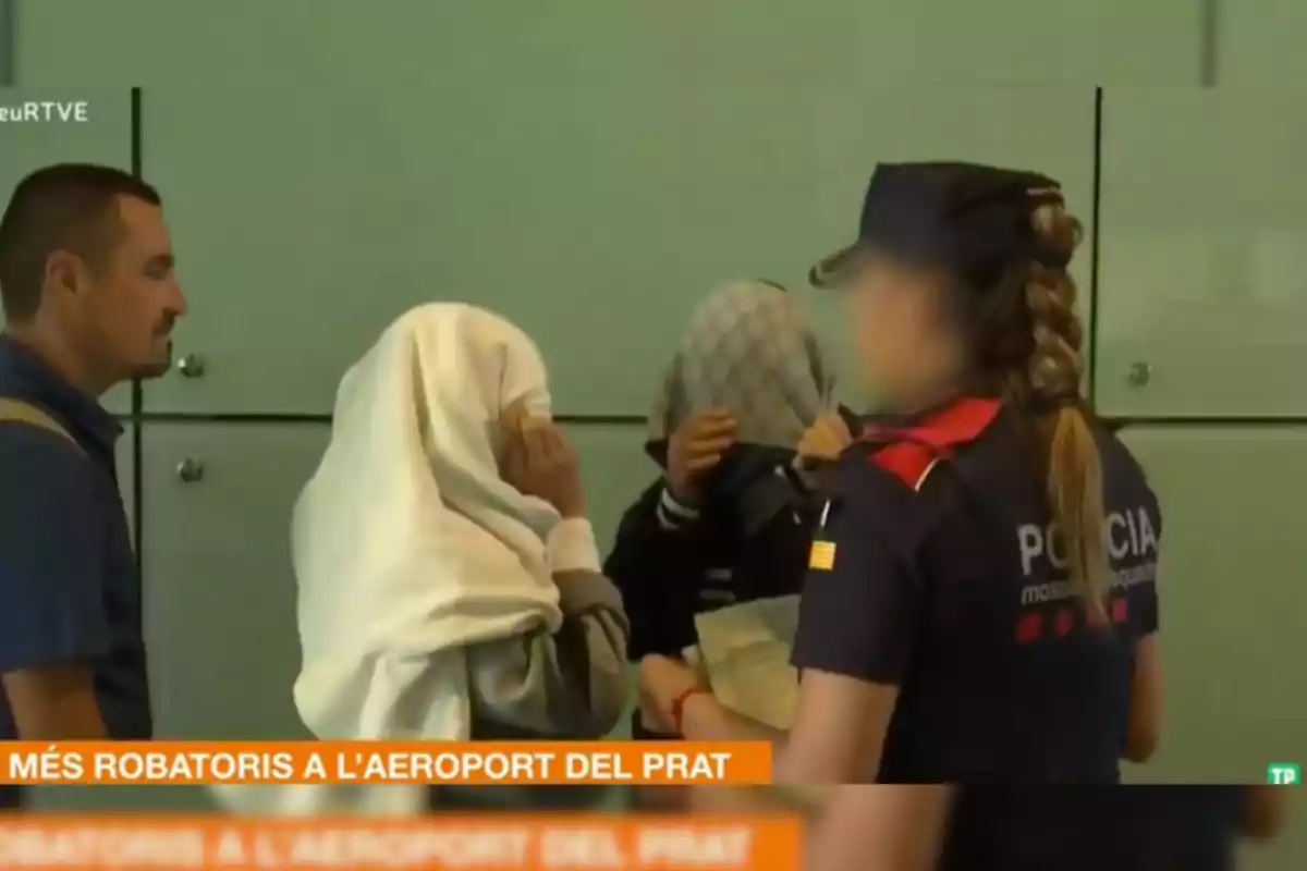 Policías y dos personas con la cara cubierta en el Aeropuerto del Prat.