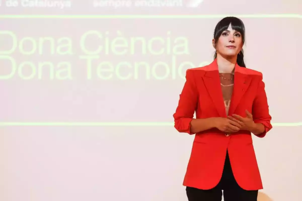 Gina Tost está de pie frente a una pantalla que dice "Dona Ciència Dona Tecnologia".