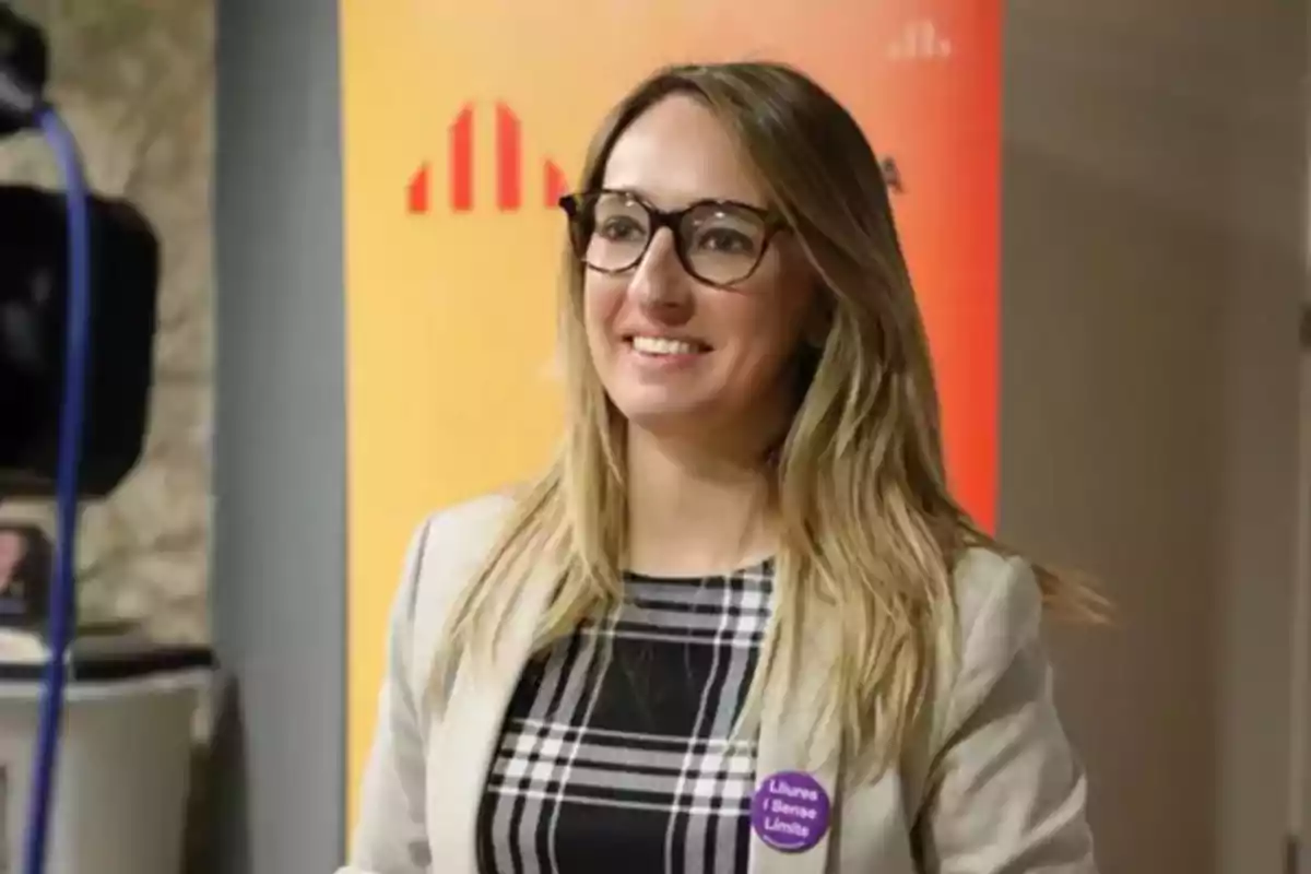 Etna Estrems, diputada de ERC en el Congreso de los Diputados, sonriendo frente a un fondo naranja.