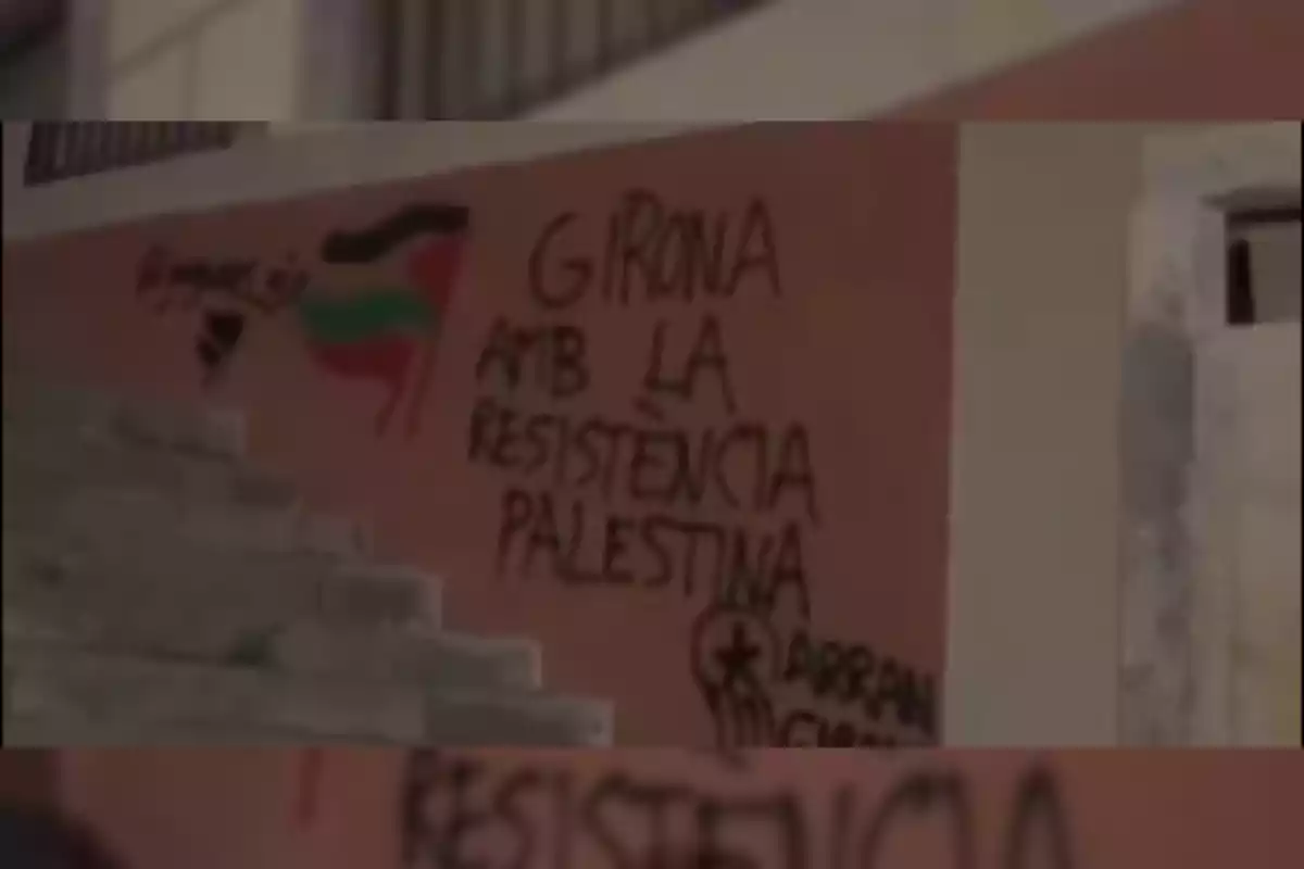 Un grafiti en una pared con el texto "Girona amb la resistència palestina" y una bandera palestina pintada al lado.