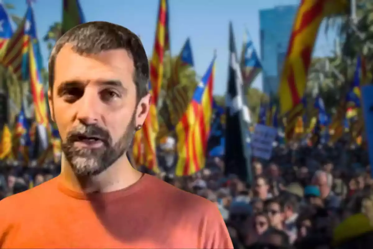 Jordi Borràs está en primer plano, mientras que al fondo se observa una multitud con banderas coloridas.