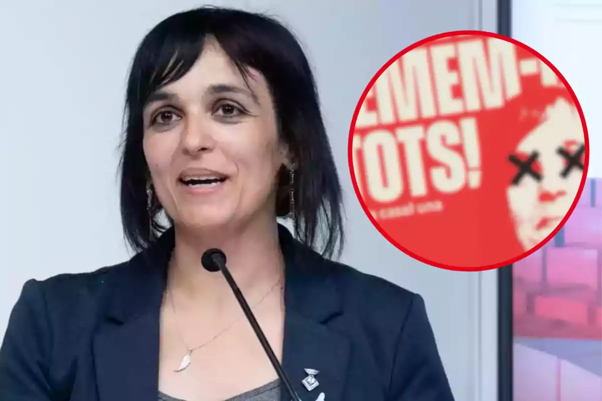 Sílvia Orriols hablando en un micrófono con un cartel rojo en el fondo que tiene una cara con ojos tachados.