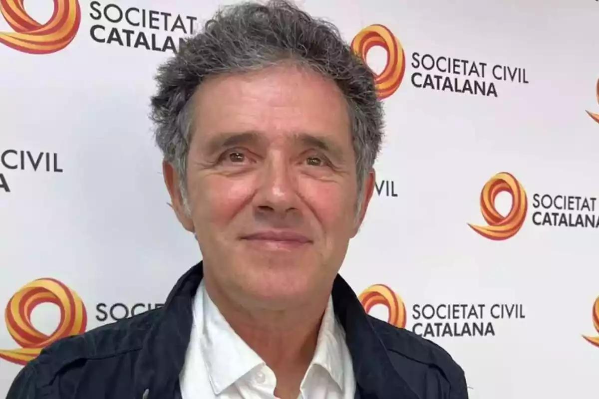 Primer plano de Àlex Ramos delante de un photocall con varios logos de Societat Civil Catalana