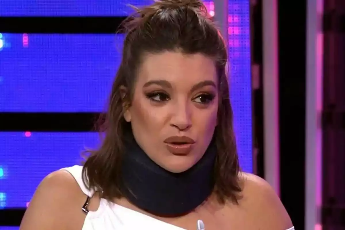 Ana Guerra con collarín ortopédico hablando en Tu Cara Me Suena con fondo iluminado en tonos morados