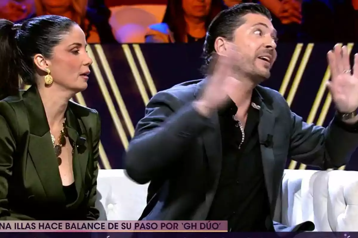 Dos personas están sentadas en un set de televisión de De Viernes, Ángel Cristo JR gesticula con las manos mientras Ana Herminia escucha atentamente. Dos personas están sentadas en un set de televisión de De Viernes, Ángel Cristo JR gesticula con las manos mientras Ana Herminia escucha atentamente.