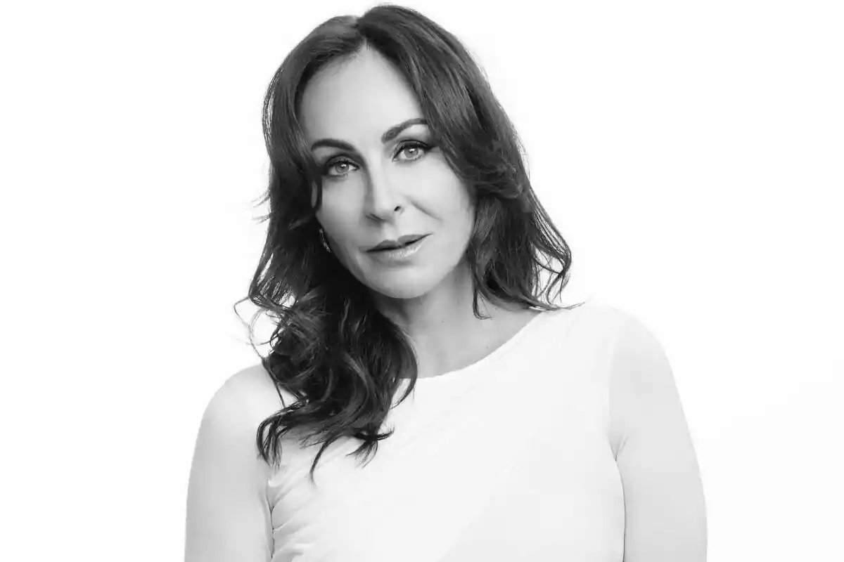 Ana Milán con cabello largo y oscuro con expresión seria vestida con blusa clara en una fotografía en blanco y negro sobre fondo blanco