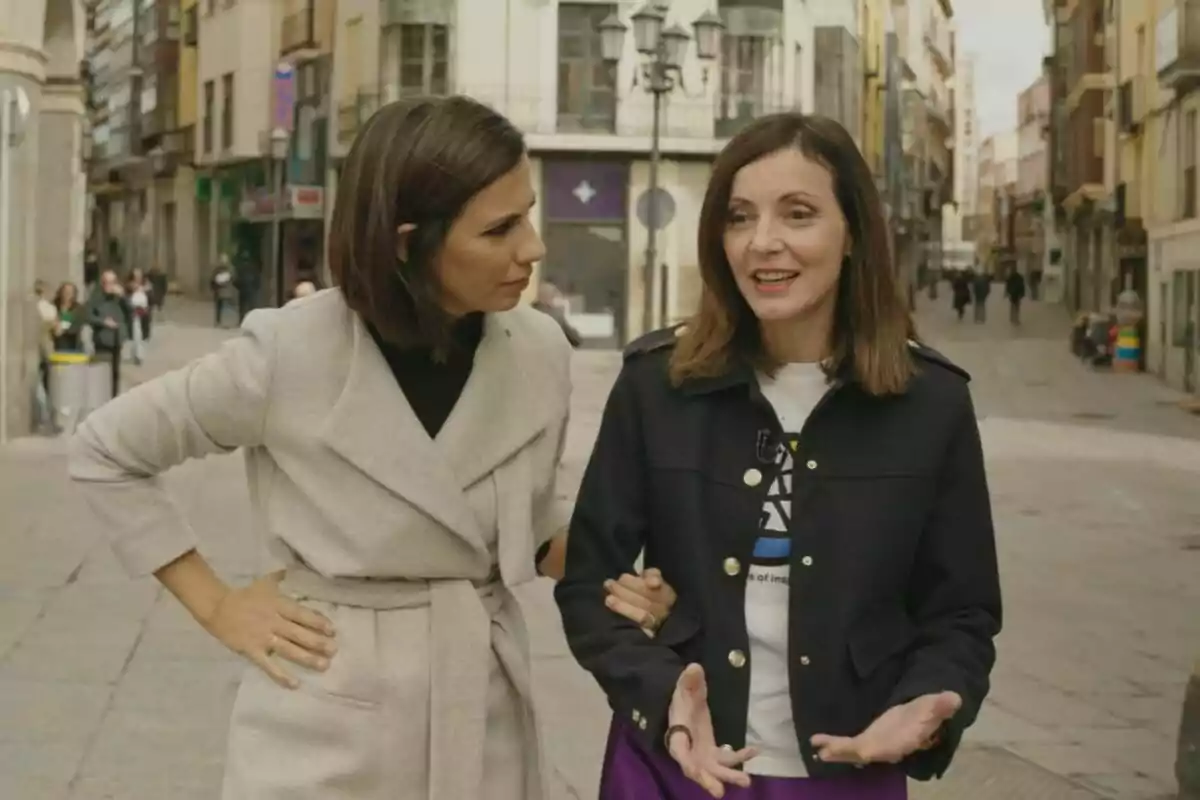 Ana Pastor y Nevenka Fernández conversando mientras caminan por una calle urbana en El Objetivo.