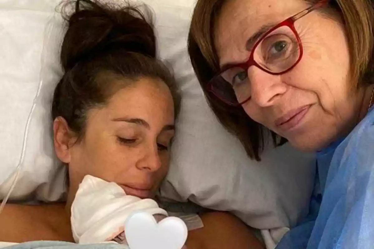 Anabel Pantoja en una cama de hospital sostiene a un bebé mientras su madre Merchi con gafas sonríe a la cámara.