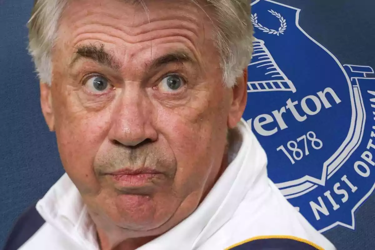 Carlo Ancelotti con cara de susto y los ojos bien abiertos al lado de un escudo del Everton