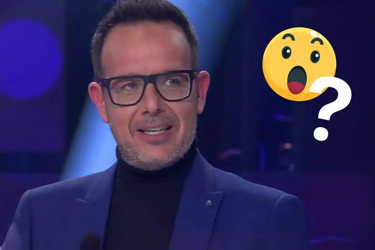 Hombre con gafas y barba, vestido con un traje azul, acompañado de un emoji sorprendido con un signo de interrogación.