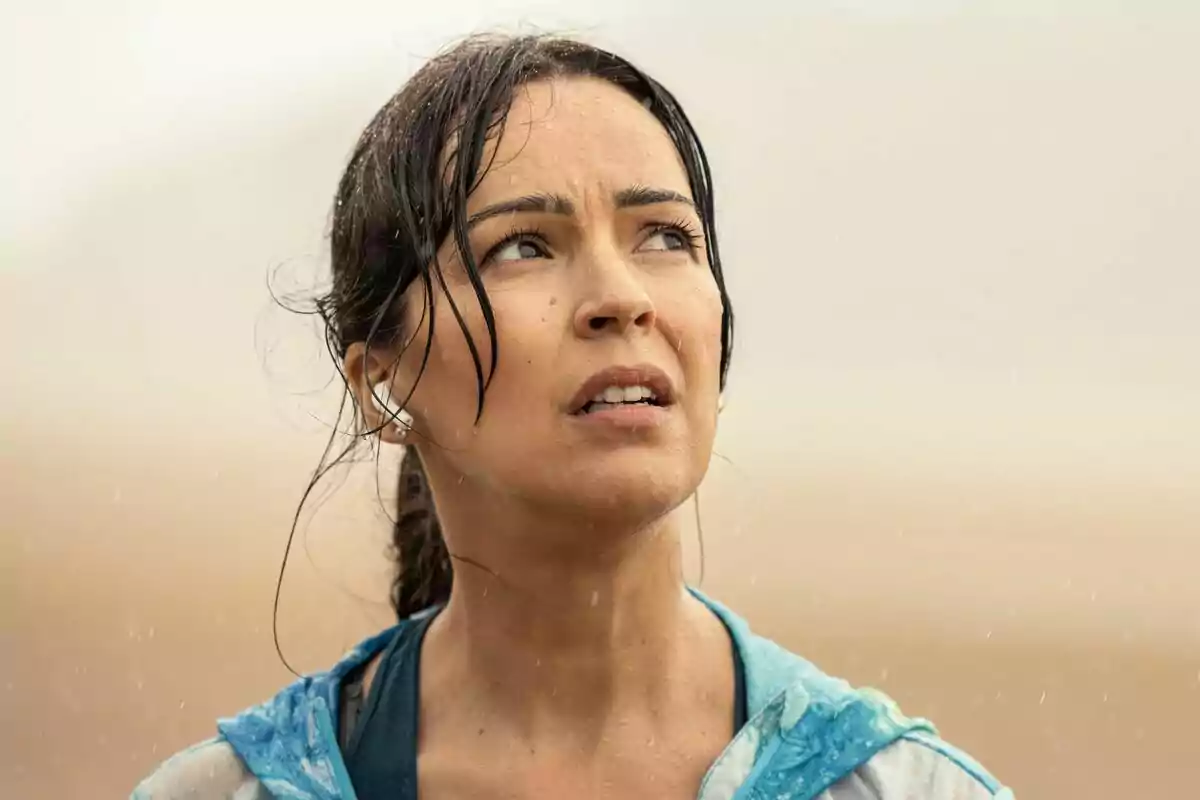 Fotografía de Verónica Sánchez con cabello mojado y expresión preocupada mirando hacia arriba en un día lluvioso en la serie Ángela