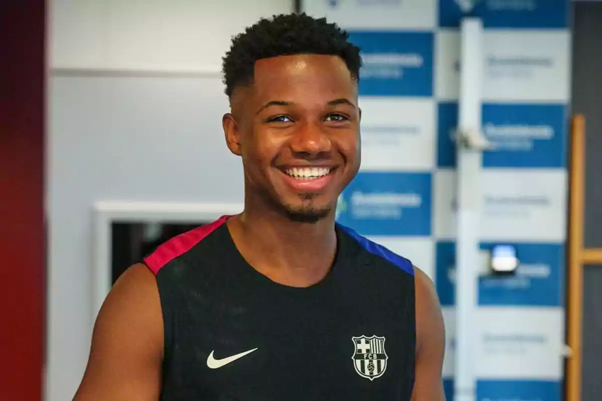 Un hombre joven sonriente con una camiseta sin mangas del FC Barcelona.