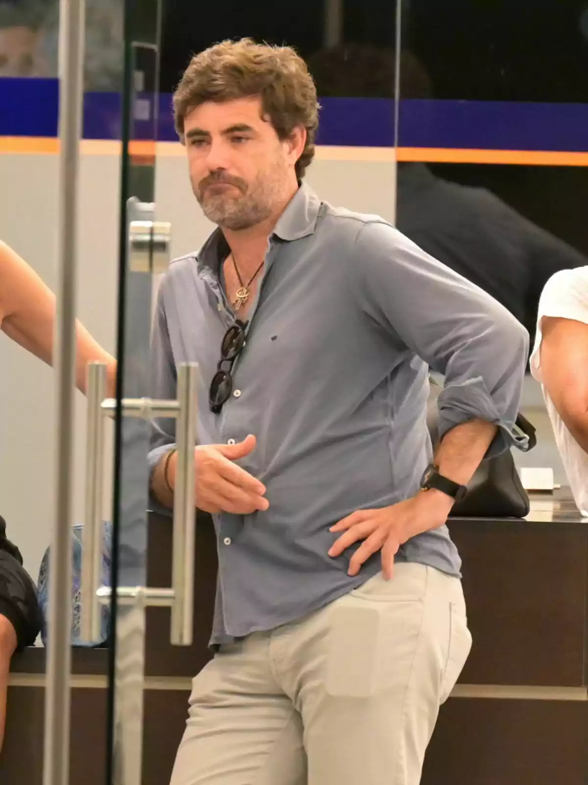 Antonio Matos con barba y cabello rizado, vestido con una camisa gris y pantalones claros, está apoyado en un mostrador con una mano en la cadera y la otra sosteniendo unas gafas de sol. Antonio Matos con barba y cabello rizado, vestido con una camisa gris y pantalones claros, está apoyado en un mostrador con una mano en la cadera y la otra sosteniendo unas gafas de sol.