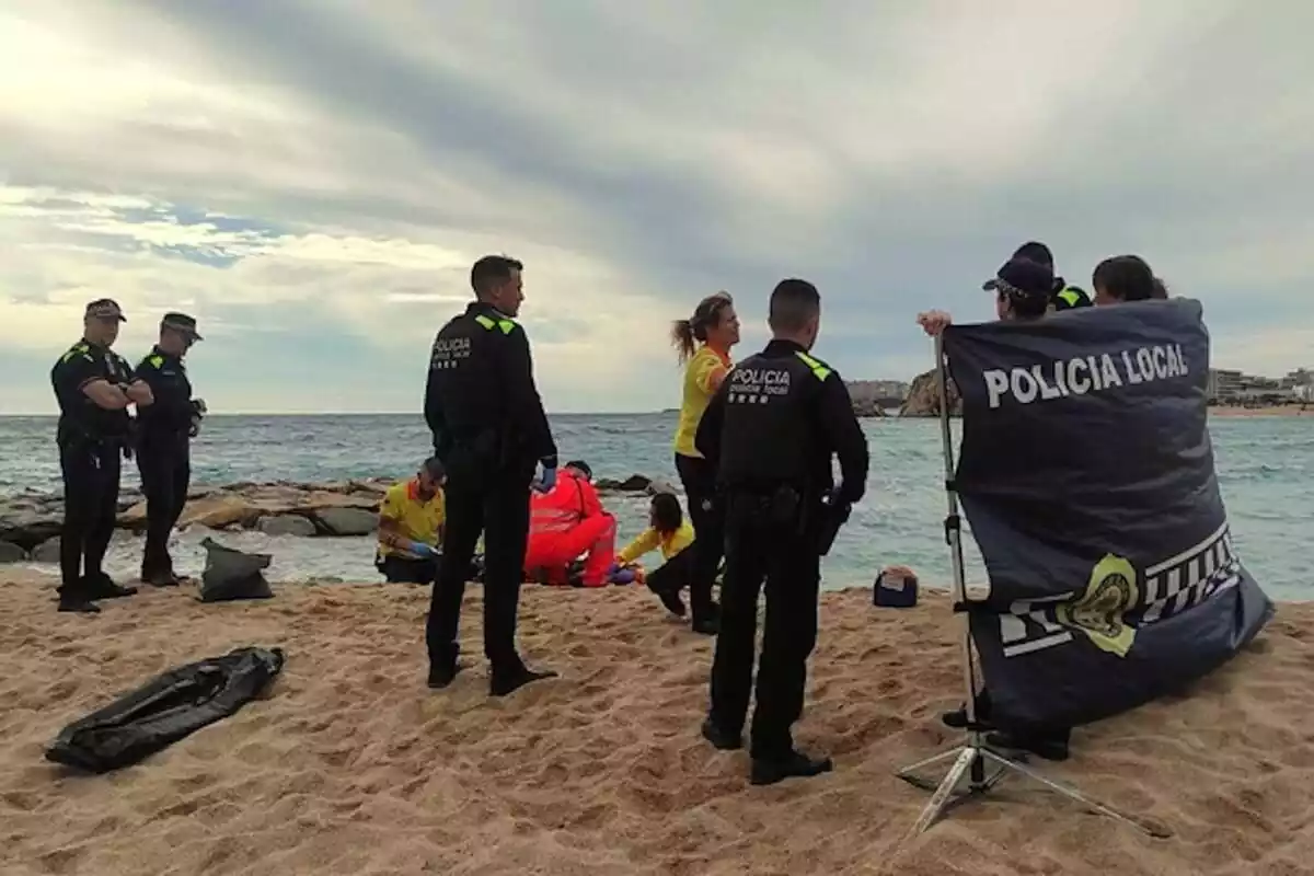 Imagen de la Policía Local de Blanes y de personal sanitario en la playa en la cual ha aparecido el cadáver de la mujer