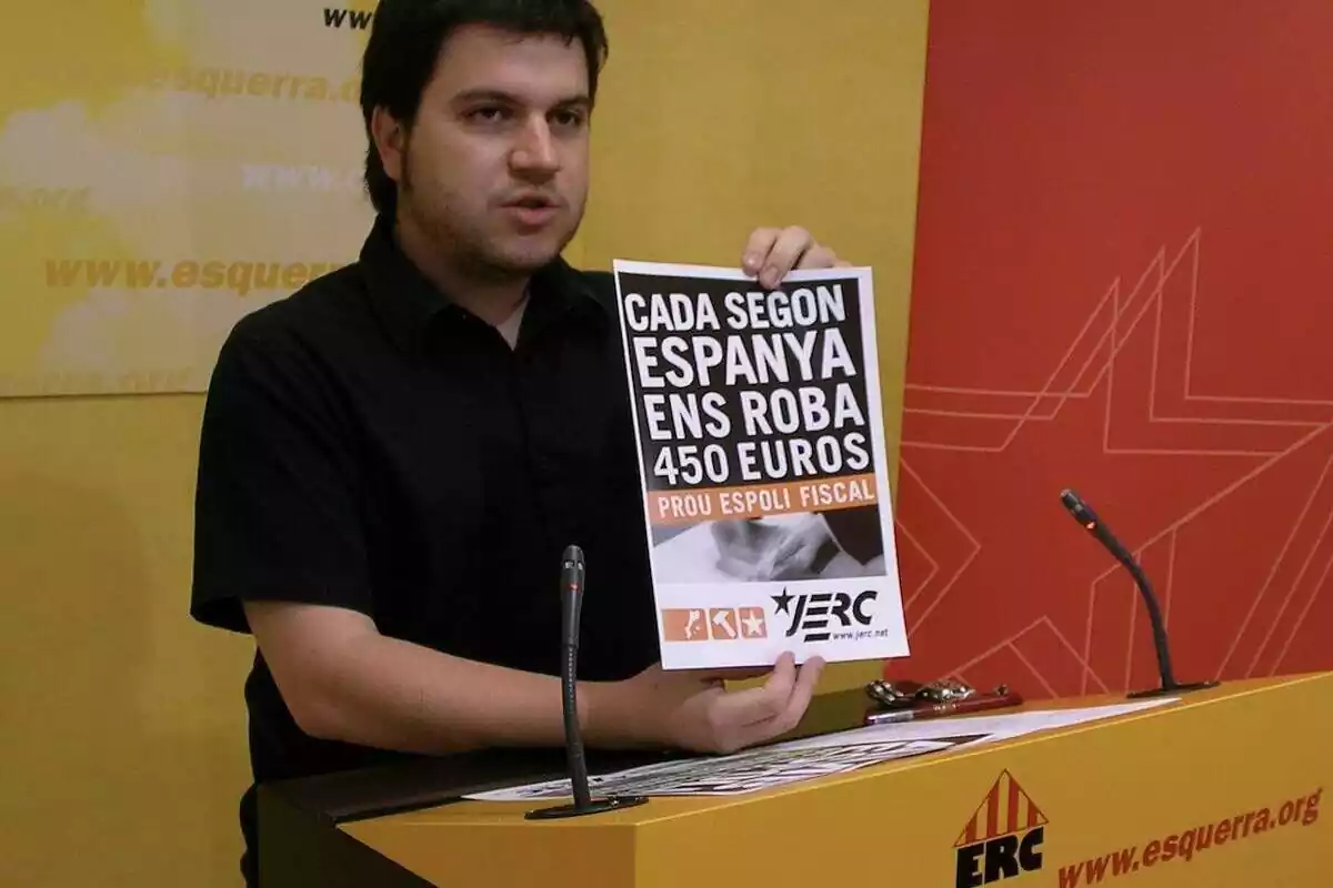 plano medio de Pere Aragonès hablando y sosteniendo un cartel de JERC donde pone "cada segundo España nos roba 450 euros"