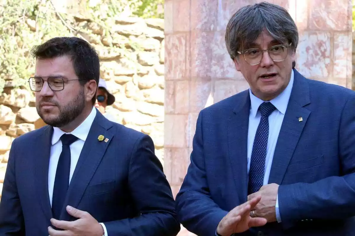 Plano medio de Pere Aragonès con cara de asco y Carles Puigdemont hablando
