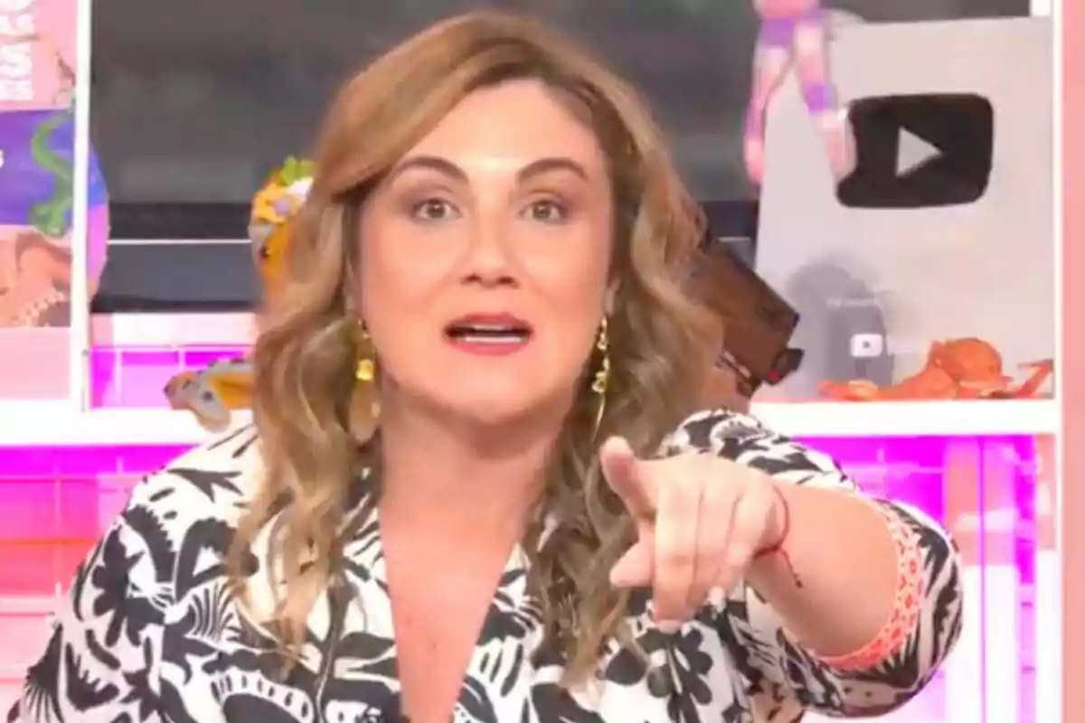 Carlota Corredera con cabello ondulado y rubio señala hacia adelante en un entorno colorido con un botón de reproducción de YouTube en el fondo en 'Tentáculos'.