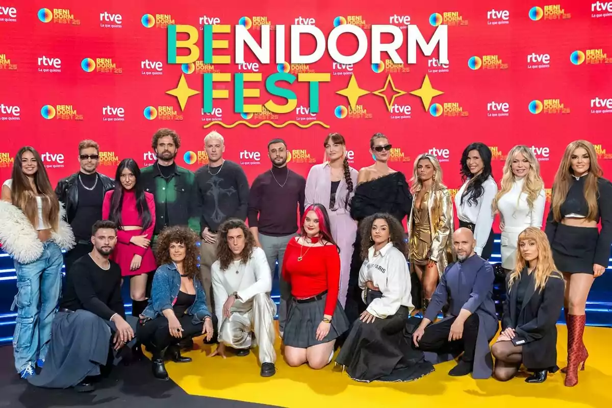 Un grupo de personas posando en el evento Benidorm Fest frente a un fondo rojo con logotipos de RTVE.