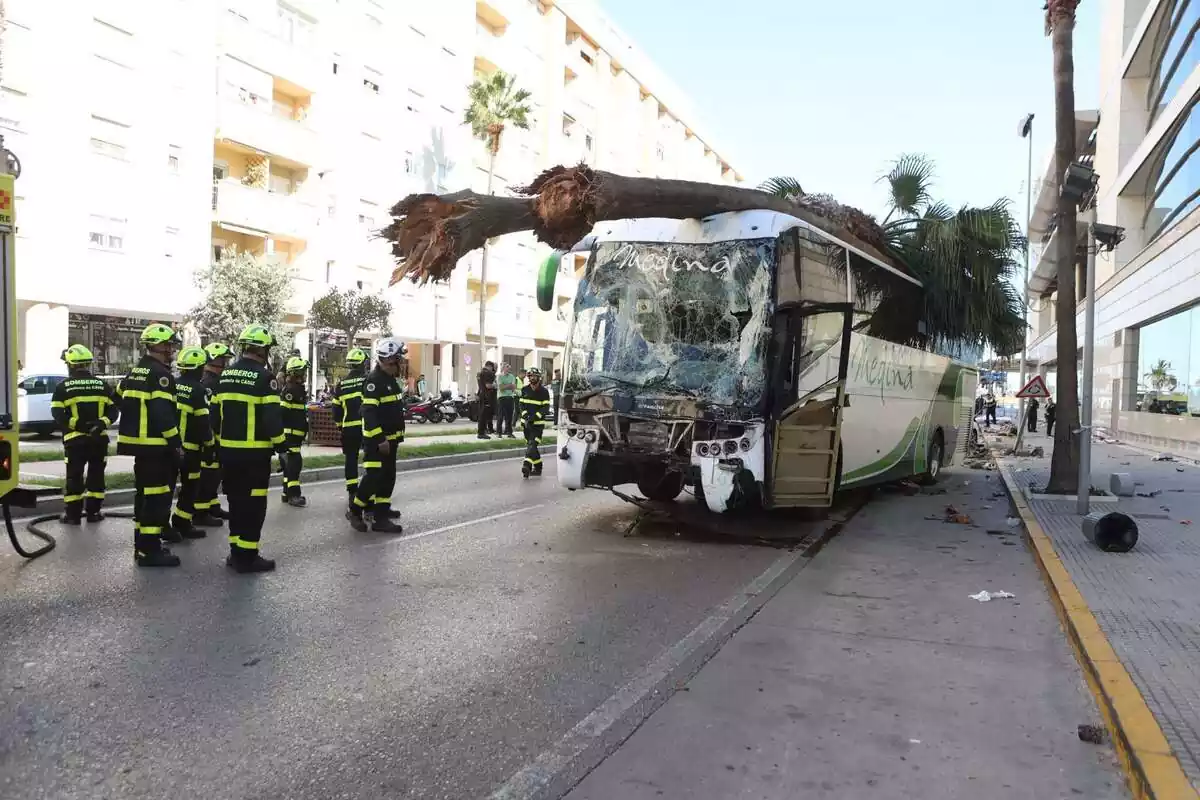 Bomberos delante de un autobús accidentado