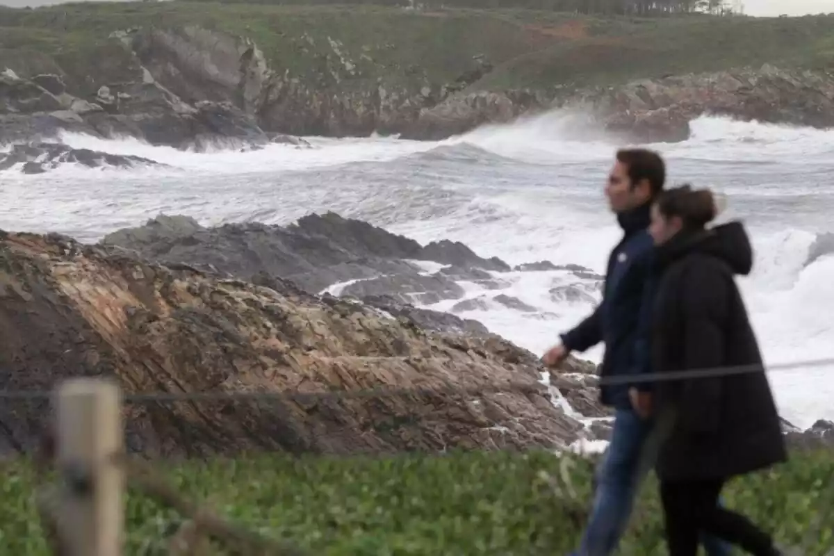 Una pareja camina junto al mar con altas olas