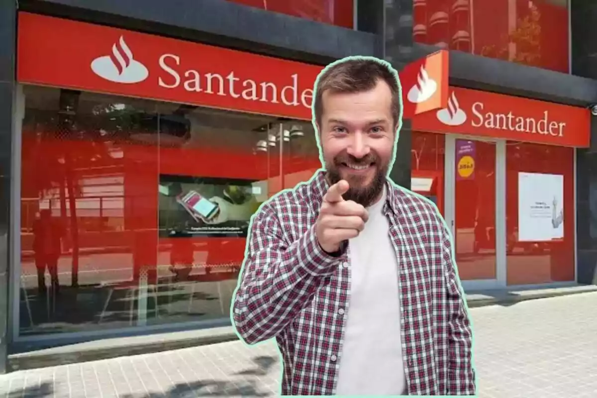 Un hombre sonriente con barba y camisa a cuadros señalando hacia adelante, con una sucursal del banco Santander de fondo.