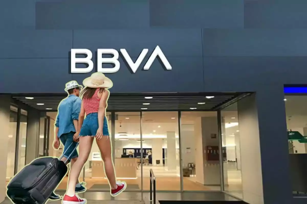 Dos personas con maletas entrando a una sucursal de BBVA.