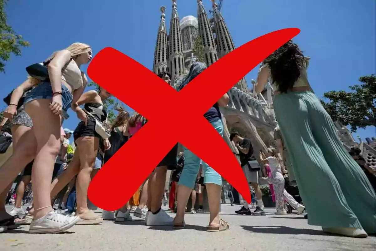 Personas caminando frente a la Sagrada Familia con una gran X roja sobre la imagen.