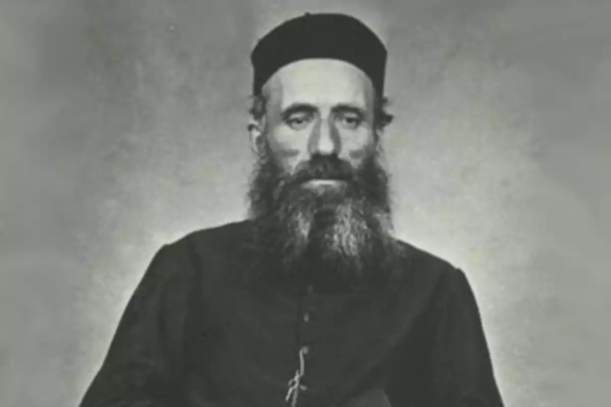 Fotografía antigua en blanco y negro de un hombre con barba larga y gorro oscuro, vistiendo ropa formal Fotografía antigua en blanco y negro de un hombre con barba larga y gorro oscuro, vistiendo ropa formal