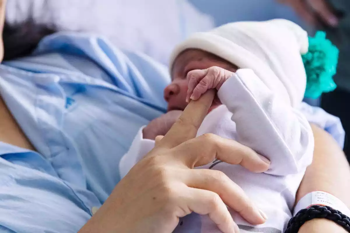 María Liz da un dedo a su hijo Erik, que ha sido el primer bebé nacido en 2024 en Madrid, en el Hospital Universitario La Paz, a 1 de enero de 2024, en Madrid (España)
