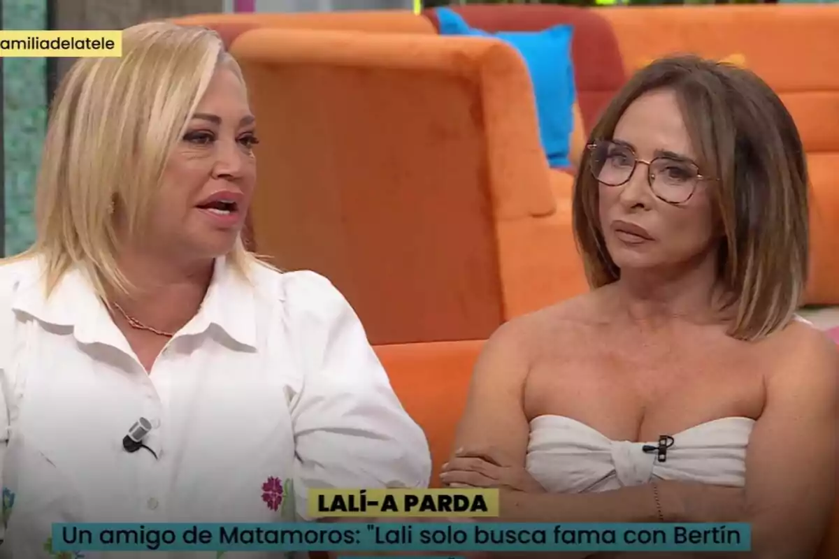 Belén Esteban y María Patiño están sentadas en un set de televisión, una de ellas lleva una camisa blanca y la otra un top blanco, ambas parecen estar en una conversación seria en La Familia de la Tele. Belén Esteban y María Patiño están sentadas en un set de televisión, una de ellas lleva una camisa blanca y la otra un top blanco, ambas parecen estar en una conversación seria en La Familia de la Tele.