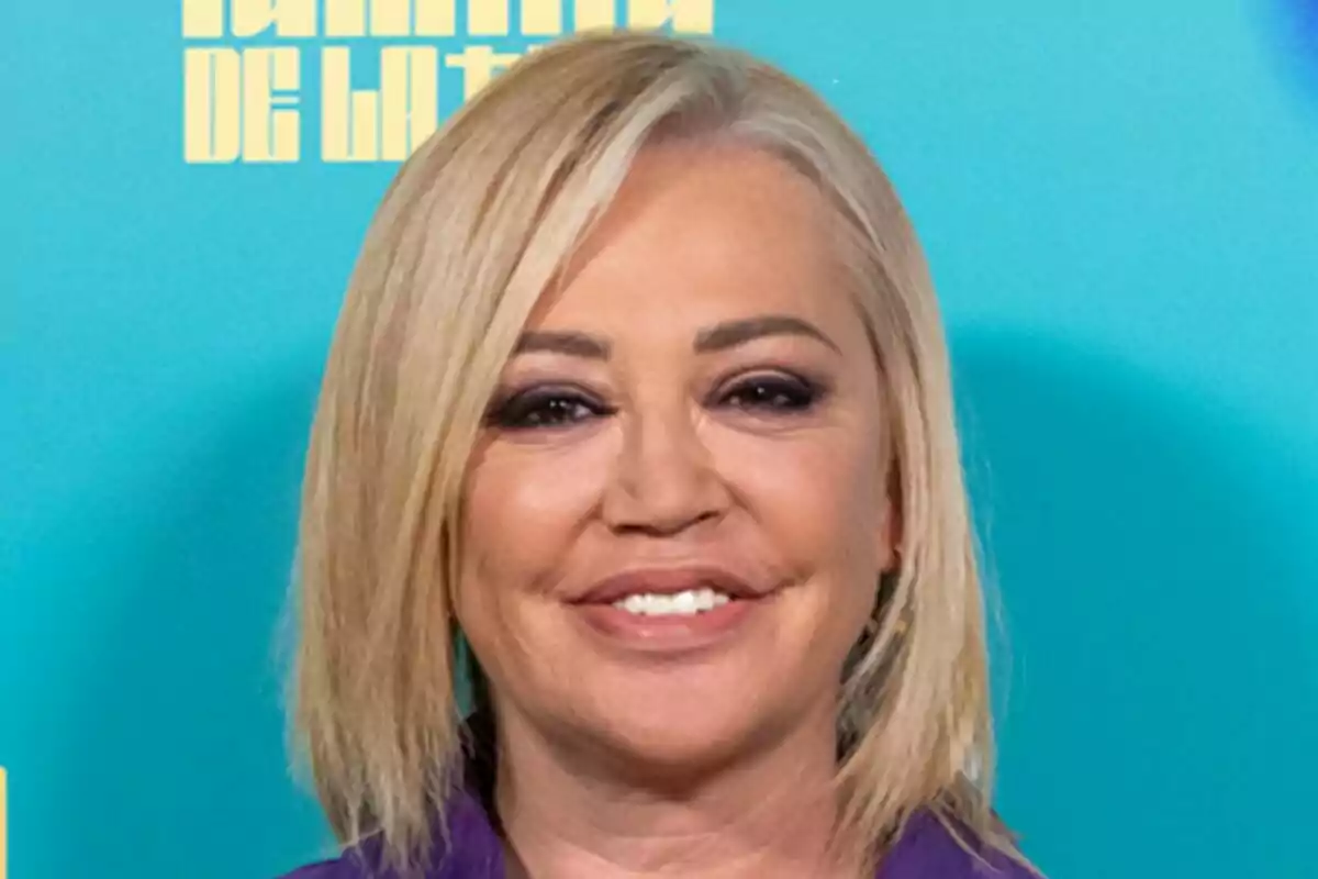 Belén Esteban con cabello rubio y sonrisa frente a un fondo azul en la presentación de La Familia de la Tele.