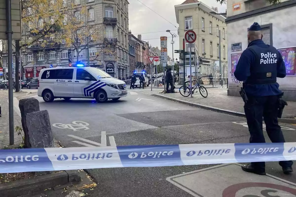 Calle de Bruselas acordonada por la policía belga, con un agente de espaldas y un coche policial cruzado en la calle