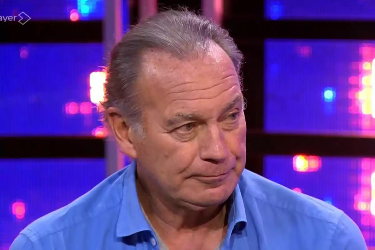 Bertín Osborne mayor con camisa azul en un set de televisión iluminado con luces de colores en Tu Cara Me Suena.