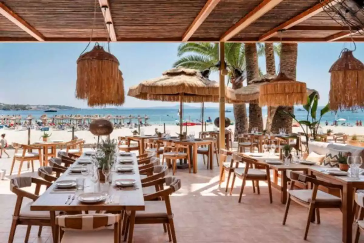 Restaurante en la playa con una decoración de color madera y unas lamparas muy ostentosas