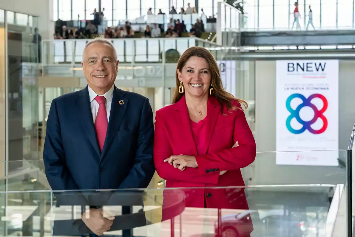 Dos personas posan sonriendo en un entorno moderno con un cartel de BNEW al fondo.