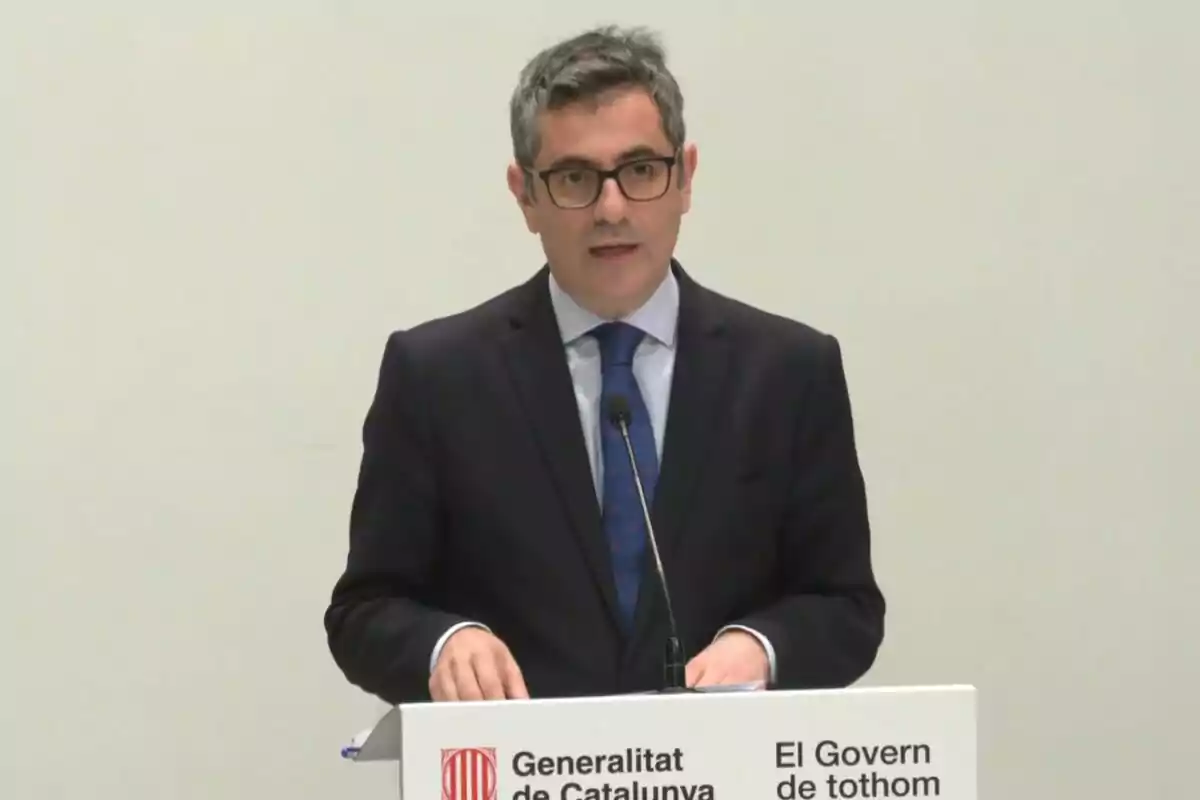 Un hombre con gafas y traje oscuro habla en un podio con el logotipo de la Generalitat de Catalunya.