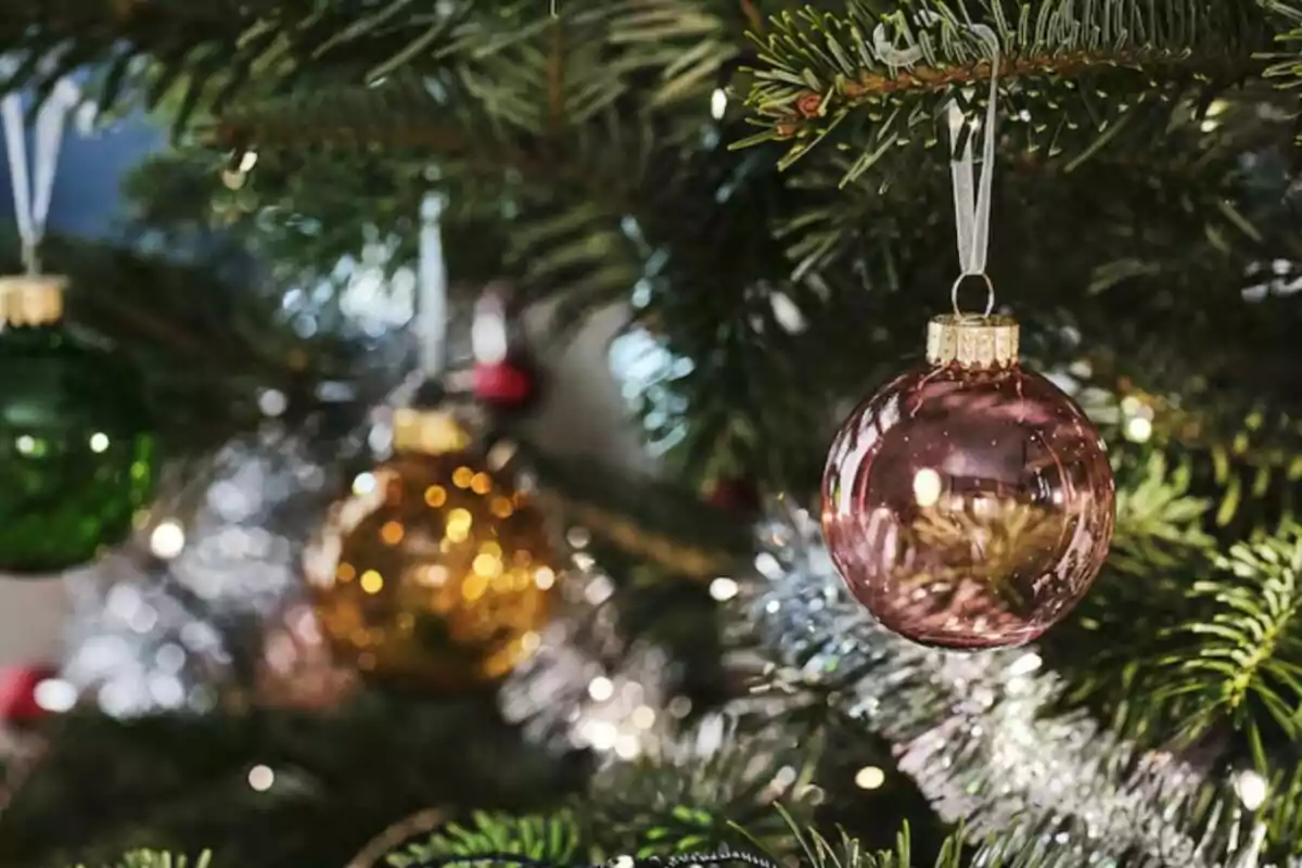 Adornos navideños colgando de un árbol de Navidad con luces brillantes. Adornos navideños colgando de un árbol de Navidad con luces brillantes.