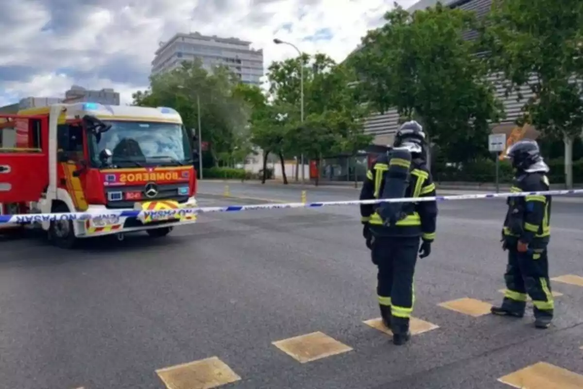 Dos bomberos y un vehículo en medio del Paseo de la Castellana de Madrid con una cinta policial