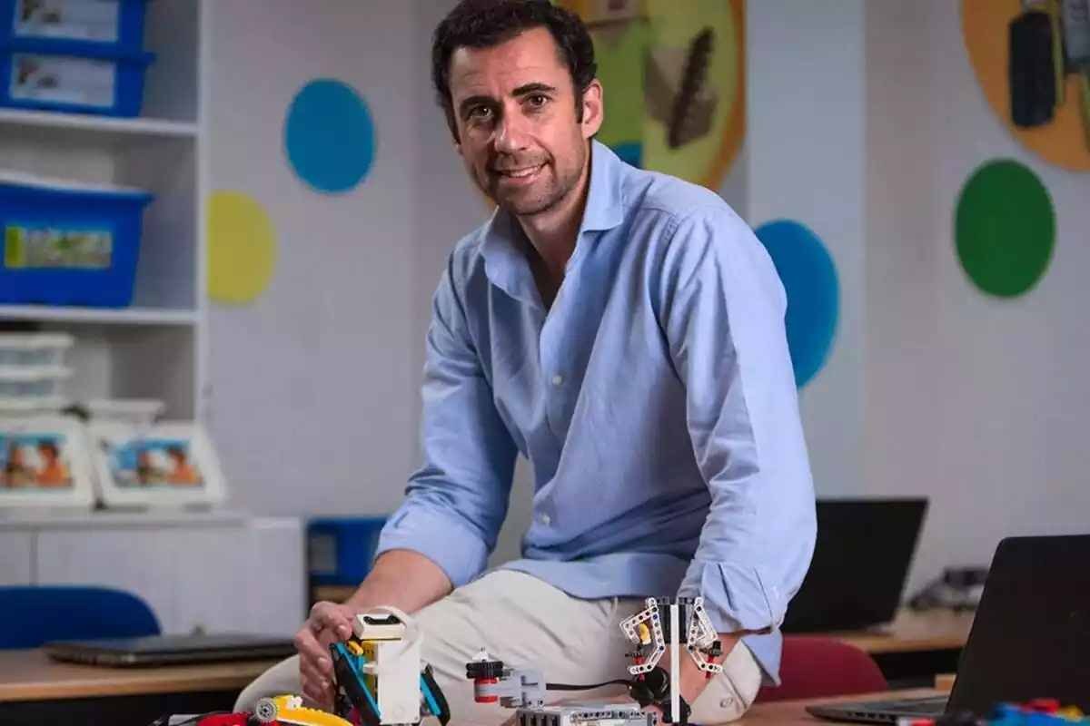 Borja Templado, fundador del proyecto Robots in Action, sentado encima de una mesa con rostro sonriente