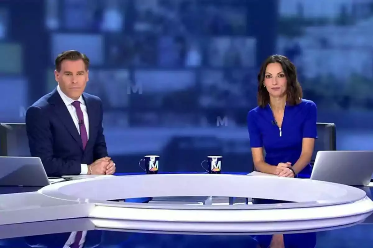 Bricio Segovia y Laila Jiménez sentados en el plató de Informativos Telecinco con una mesa blanca y tazas de café frente a ellos.