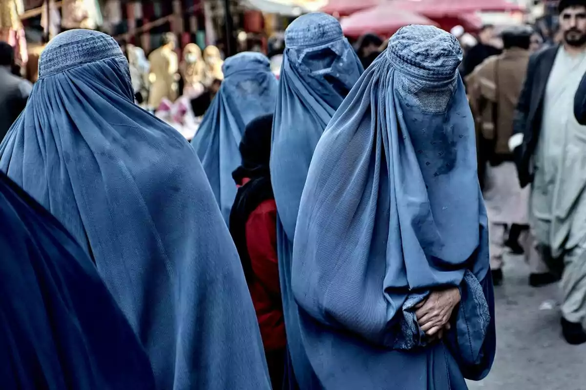 Un grupo de mujeres con burkas azules camina por un mercado concurrido en Afganistán