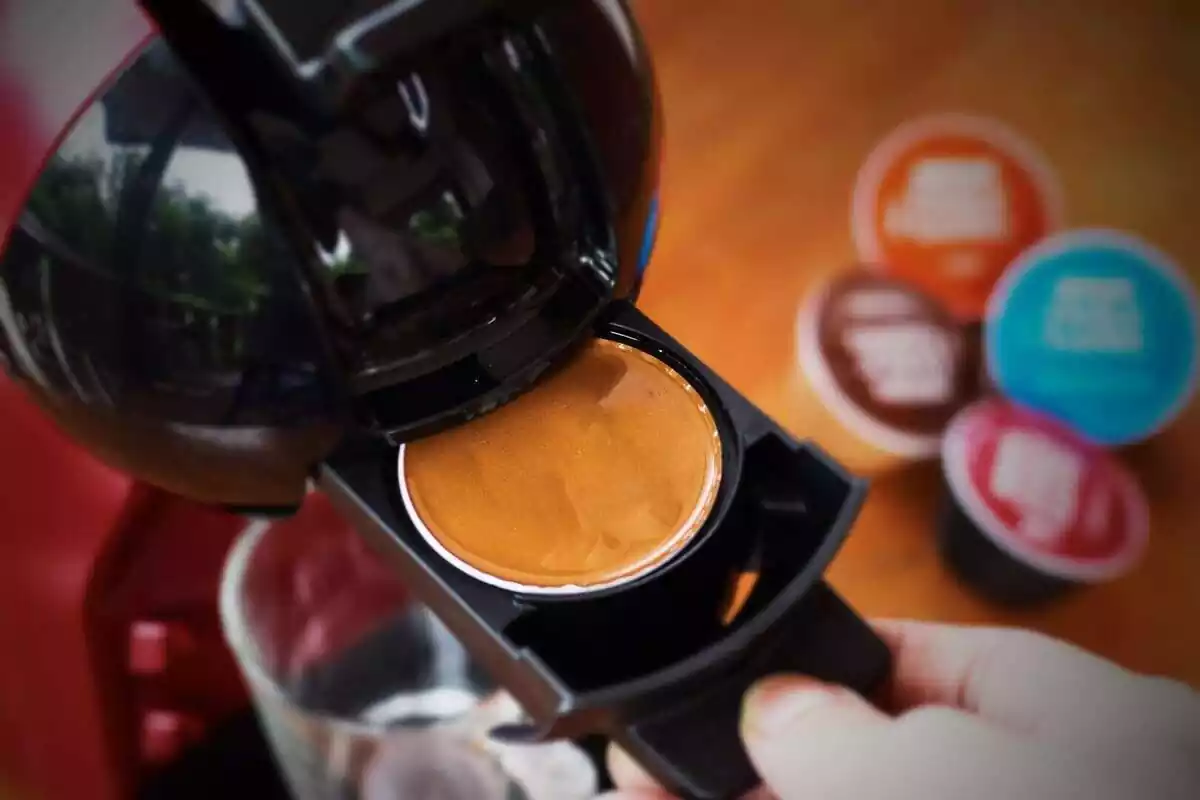 Primer plano de una persona cogiendo un café de una cafetera con cápsulas
