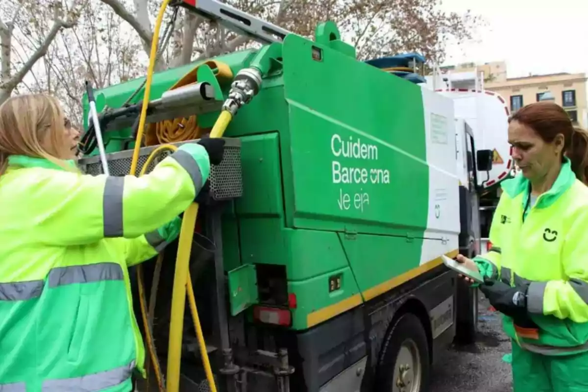 Dos trabajadoras de limpieza urbana en Barcelona, vestidas con uniformes de alta visibilidad, operan un camión de limpieza verde. Dos trabajadoras de limpieza urbana en Barcelona, vestidas con uniformes de alta visibilidad, operan un camión de limpieza verde.