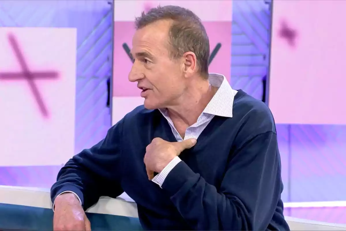 Alessandro Lequio de perfil con suéter azul y camisa blanca habla gesticulando en 'Vamos a ver' con fondo de colores claros. Alessandro Lequio de perfil con suéter azul y camisa blanca habla gesticulando en 'Vamos a ver' con fondo de colores claros.