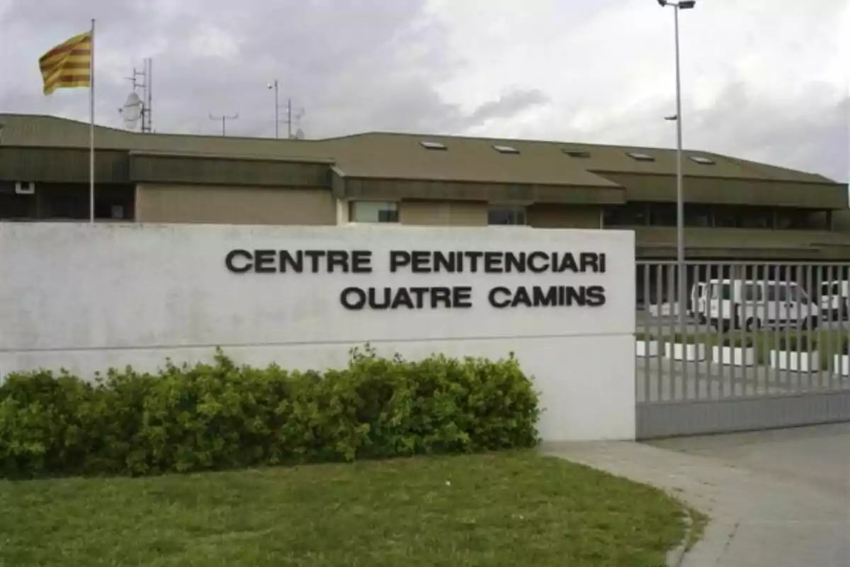 Entrada del Centre Penitenciari Quatre Camins con una bandera catalana ondeando en un mástil y un edificio de fondo.