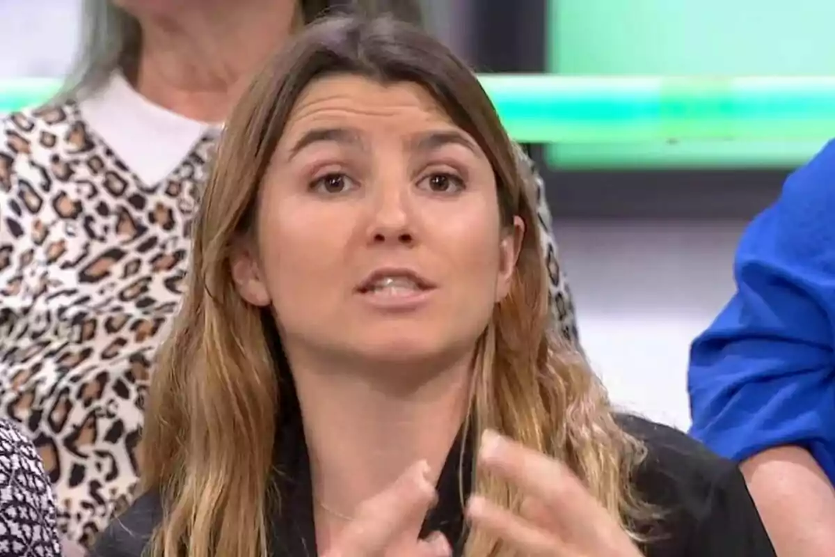 Mujer hablando con expresión seria en un programa de televisión, con personas sentadas al fondo. Mujer hablando con expresión seria en un programa de televisión, con personas sentadas al fondo.