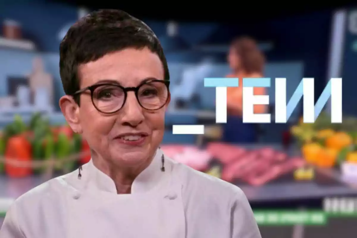 Carme Ruscalleda con gafas y cabello corto lleva un uniforme de chef en un entorno de cocina con vegetales desenfocados al fondo y el logo de Tot es Mou en el centro.