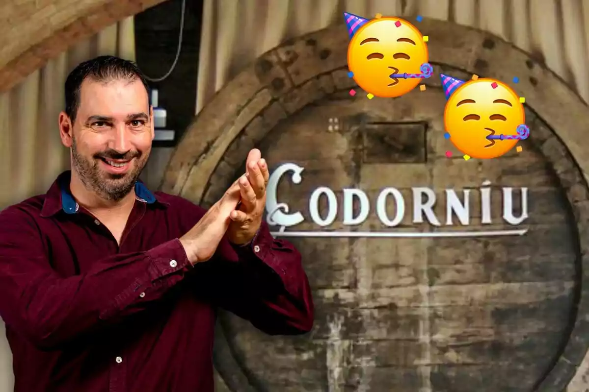 Un hombre sonriente con camisa roja aplaudiendo frente a un barril de madera con la palabra "Codorníu" y dos emojis de fiesta.